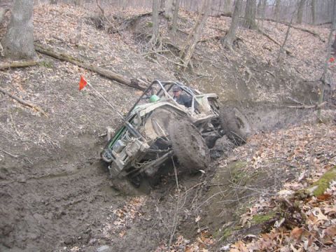1992 Ford Bronco - This buggy is navigating a challenging muddy terrain on a wooded trail.