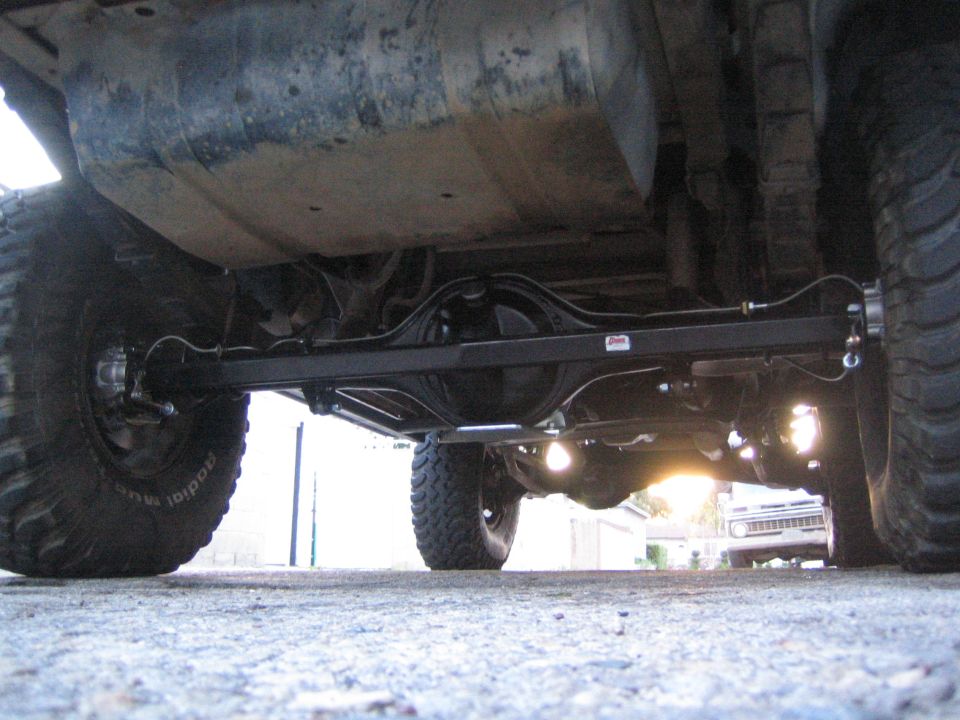 Underside rear view of a lifted truck showing solid axle, leaf springs and mud tires