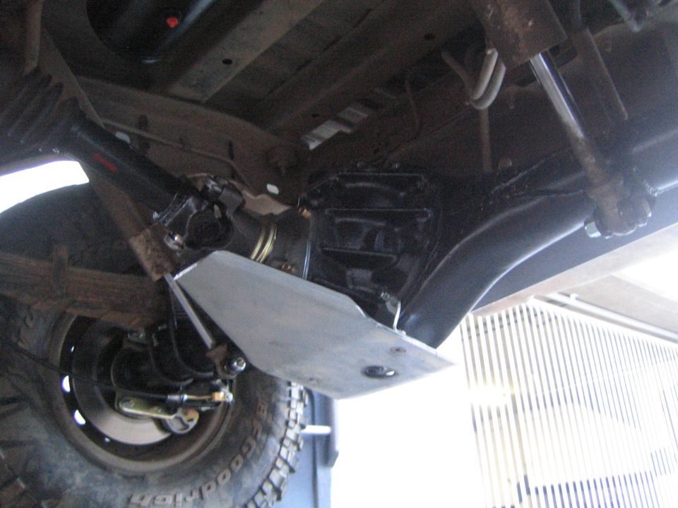 Undercarriage of a lifted truck with skid plate, leaf springs and shock absorber