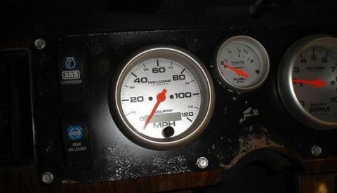 1984 Ford Bronco - Close-up of a vehicle's dashboard, showing aftermarket gauges and control switches for off-road accessories.