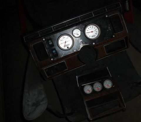 1984 Ford Bronco - A collection of aftermarket gauges and dashboard trim pieces are laid out for inspection.