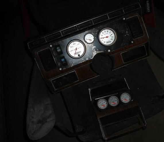 Dashboard trim with three gauges and a tachometer, showing wood grain accents