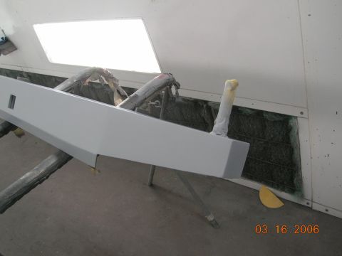 1985 Ford Bronco - A gray rear bumper is shown on a stand, likely in a repair shop or paint booth, with protective coverings on some parts.