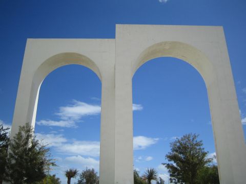1990 Ford Bronco - pair of large white concrete arches stand against a deep blue sky above trees and palms.