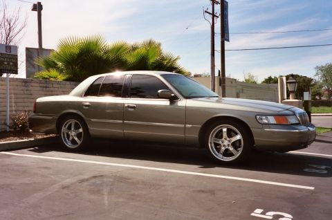 2000 Mercury Grand Marquis - A tan 2000 Mercury Grand Marquis sedan is parked in a lot on a sunny day.