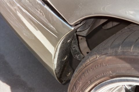 2000 Mercury Grand Marquis - The rear fender of a car shows extensive damage, including deep scratches and scuff marks.