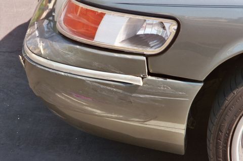2000 Mercury Grand Marquis - The front right corner of a green 2000 Mercury Grand Marquis shows extensive damage to the bumper and fender area.