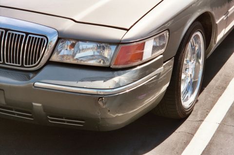 2000 Mercury Grand Marquis - The front passenger side of a Mercury Grand Marquis shows minor damage to the bumper and chrome trim.
