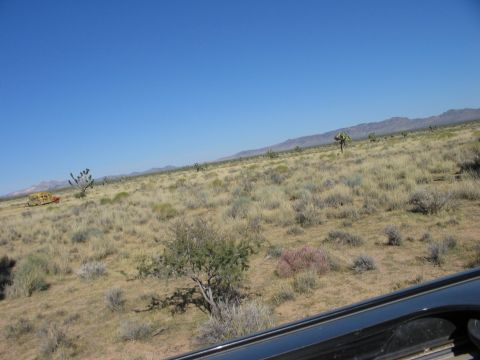 1992 Ford Bronco - A yellow vehicle sits in a vast desert landscape under a clear blue sky.