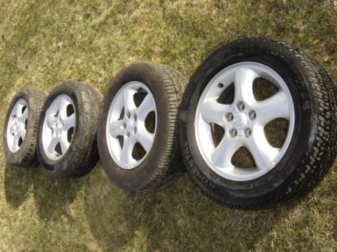 1999 Ford Taurus - Four car wheels and tires are shown on a grassy surface.