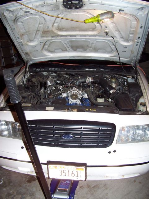 2000 Ford Crown Victoria - Front view of a 2000 Ford Crown Victoria with the hood open, showing the engine compartment.