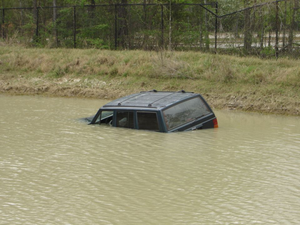 Dark 1996 Jeep Cherokee partially submerged in murky water