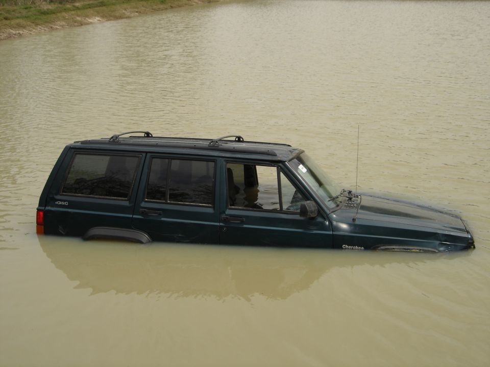 1996 Jeep Cherokee partially submerged in murky water, side view