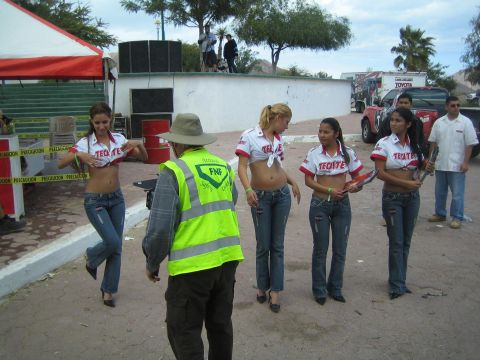 1990 Ford Bronco - group in red-and-white promotional shirts gathers with an FNF-vested official on a paved lot, with vehicles and a tent behind.