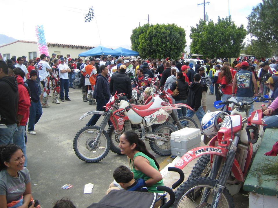 Crowd around red Honda dirt bikes parked on a street at an off-road racing event
