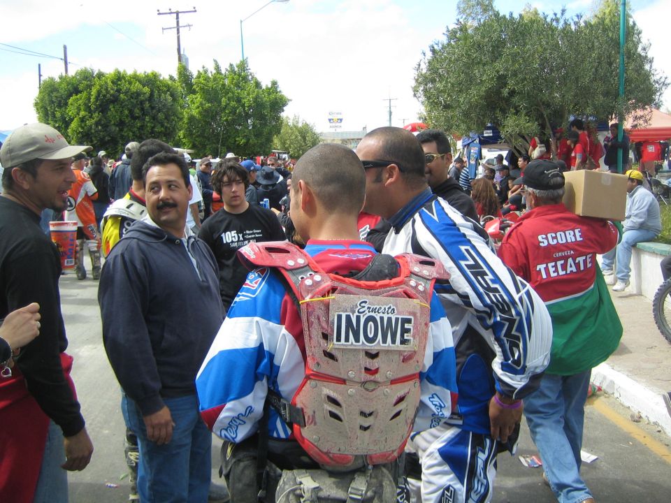 Riders in motocross chest protectors seen from behind in a crowded street