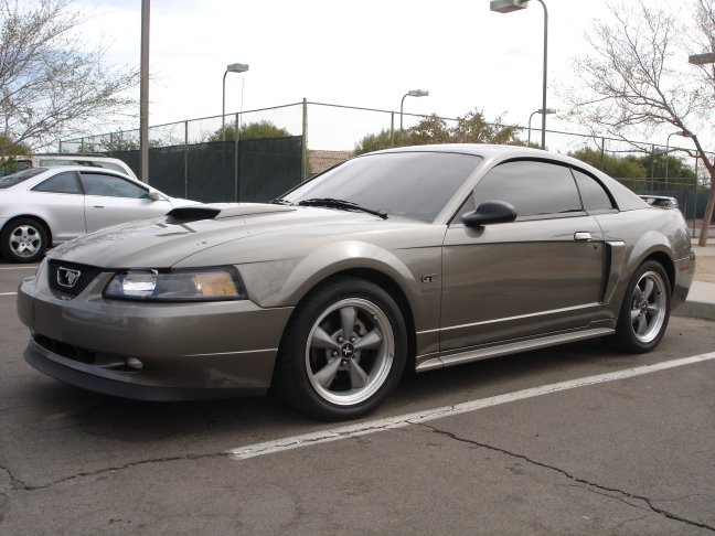 Gray Mustang GT coupe parked in a lot, three-quarter front view with hood scoop