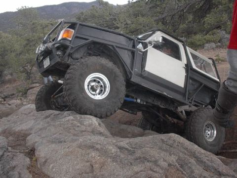 1993 Ford F-150 - This heavily modified 1993 Ford F-150 navigates a challenging rocky terrain with its large off-road tires and custom roll cage.