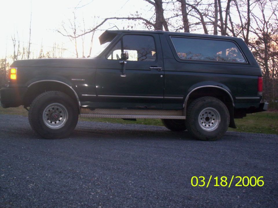 Side view of a dark green 1988 Ford Bronco with aftermarket wheels