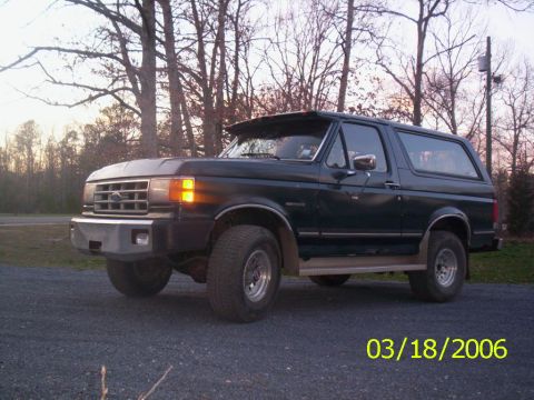1988 Ford Bronco - Ford Bronco parked outdoors with trees in the background. Date stamp visible on the image.