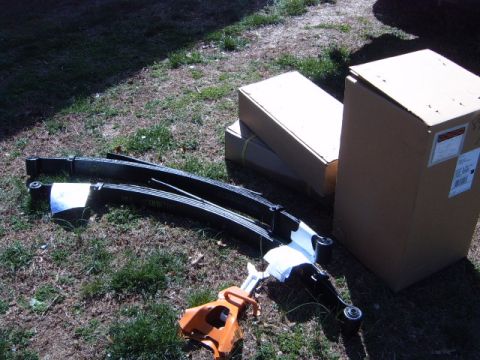 1988 Ford Bronco - Leaf springs and boxes are laid out on the grass next to an orange jack.