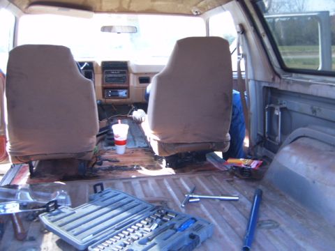 1988 Ford Bronco - The interior of a vehicle is shown with tools and a drink, suggesting ongoing work or cleaning.