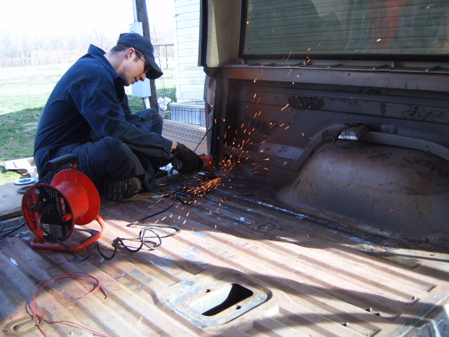 guy grinding metal in the bed of a pickup truck, sparks flying