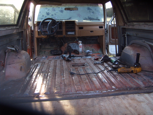 Disassembled interior of a brown 1980s Ford Bronco with tools on the floor