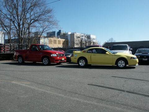 2001 Mercury Grand Marquis - Two performance vehicles, a red Ford F-150 Lightning and a yellow Ford Mustang, are parked side-by-side.
