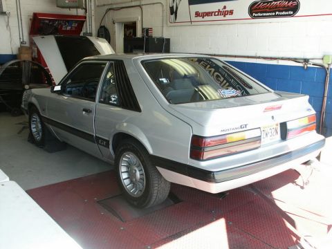 2001 Mercury Grand Marquis - A silver 1987 Ford Mustang GT hatchback is positioned on a dynamometer in a garage setting.