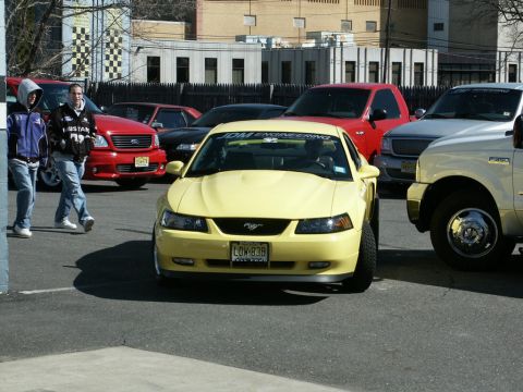 2001 Mercury Grand Marquis - A yellow 2001 Ford Mustang is parked among other vehicles, with a JDM ENGINEERING banner across the windshield.
