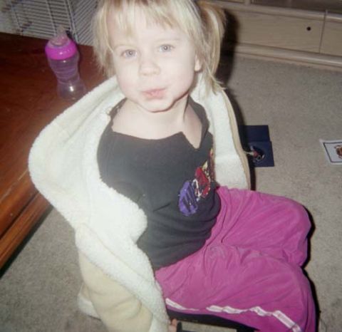 2002 Oldsmobile Aurora - A child sits wrapped in a blanket, looking towards the camera.