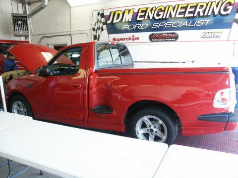 2001 Mercury Grand Marquis - A red 2001 Ford F-150 Lightning pickup truck is positioned on a dynamometer, with a "JDM ENGINEERING FORD SPECIALIST" banner in the backgro…