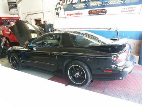 2001 Mercury Grand Marquis - A black Pontiac Firebird is positioned on a dynamometer in a garage, with its hood up and a person observing.