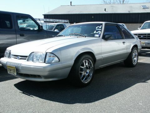 2001 Mercury Grand Marquis - A silver Ford Mustang is parked outside, with a race number '512' visible on the windshield.