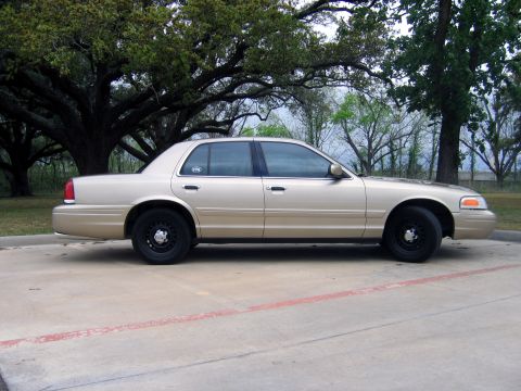 2000 Ford Crown Victoria - Side profile of a tan 2000 Ford Crown Victoria sedan parked outdoors.