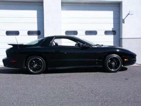 2001 Mercury Grand Marquis - Side profile of a black Pontiac Firebird with black rims and a rear spoiler.