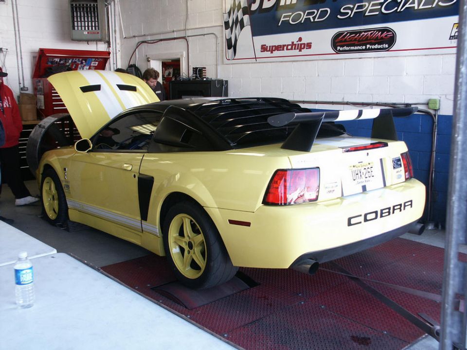 Yellow 2001 Ford Mustang Cobra convertible on a dyno, rear view