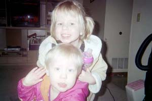 2002 Oldsmobile Aurora - A photo captures two young children, one in front of the other, smiling at the camera.