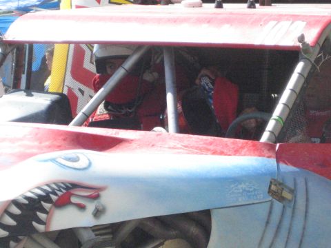 1990 Ford Bronco - Driver and co-driver seated in a red tube-frame off-road buggy with shark-mouth paint on the nose, marked number 102.