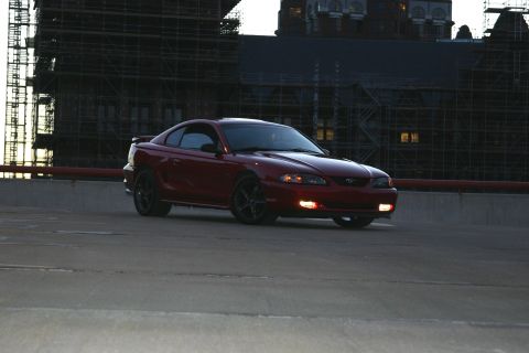 1993 Ford Probe - A red coupe with black wheels is parked in front of a building undergoing construction.