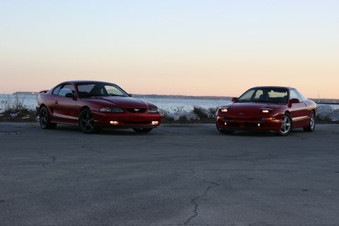 1993 Ford Probe - A 1994 Ford Mustang and a 1994 Ford Probe are parked side-by-side near the water at sunset.