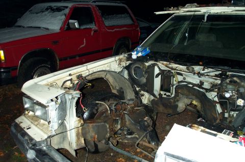 1984 Ford Bronco - Two vehicles are visible, one with its engine compartment exposed, parked outside in the snow.