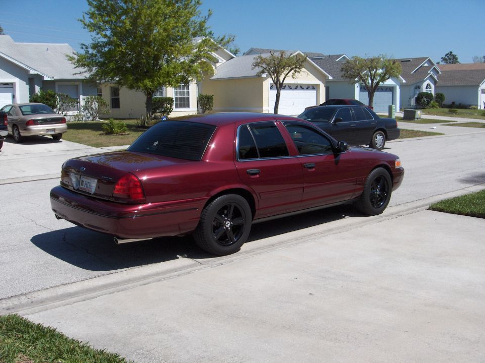 Maroon 2004 Ford Crown Victoria parked on street, other cars and houses in background