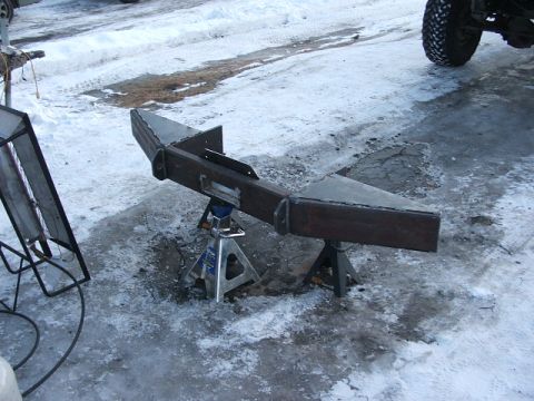1990 Chevrolet Suburban - A fabricated steel bumper is supported by jack stands on a snowy surface, with a vehicle tire visible in the background.