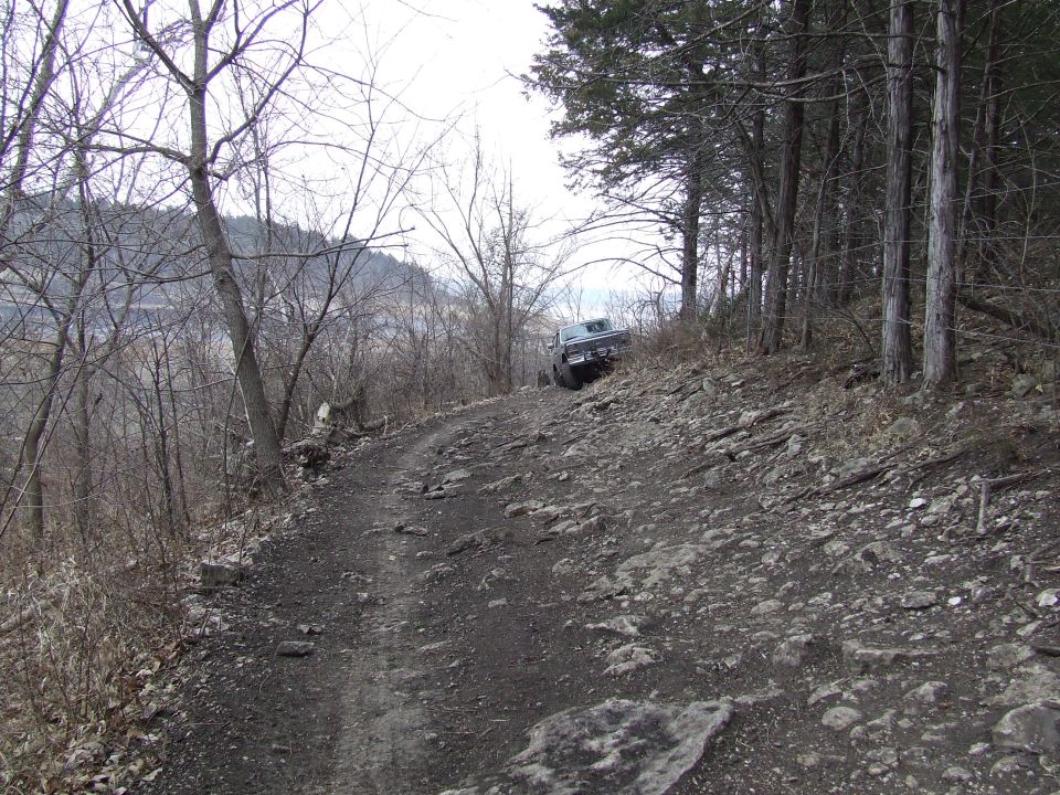 Truck on a rough, rocky trail going uphill through trees