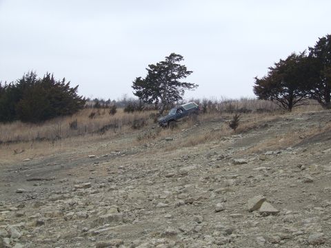 1986 Ford Bronco - Ford Bronco navigating a challenging off-road terrain under an overcast sky.