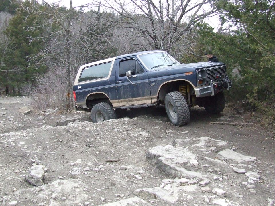 Blue 1986 Ford Bronco navigating a rocky trail