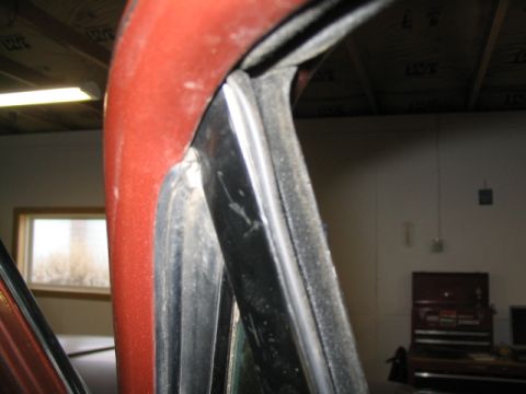 1979 Ford Bronco - Close-up view of the red door frame and window seal, showing interior details of a vehicle.