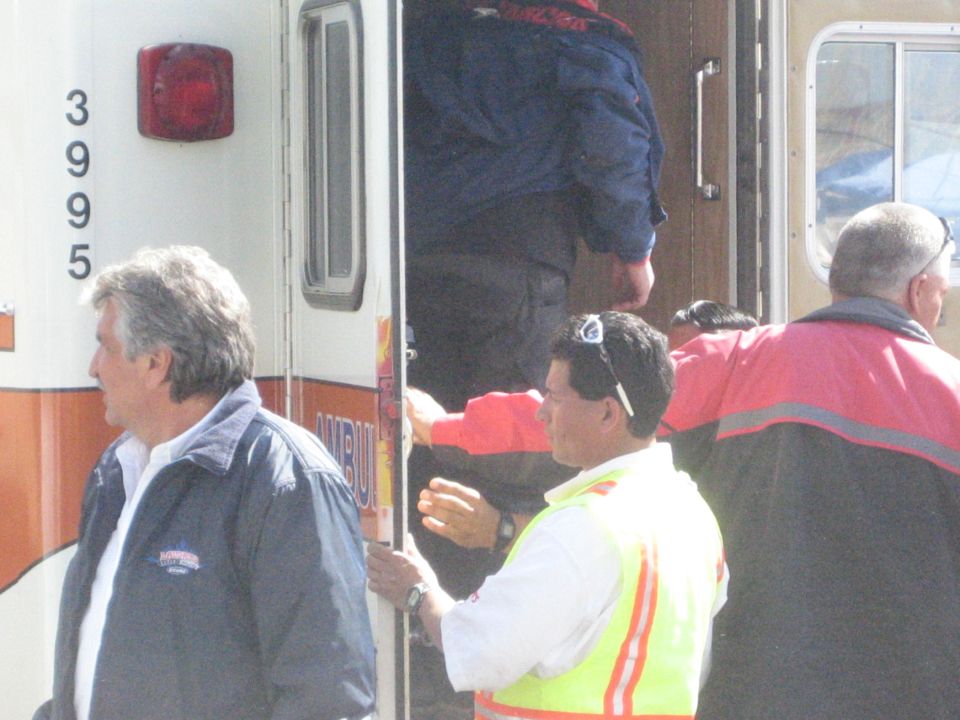 People at the rear of an ambulance numbered 3995, one in a yellow safety vest